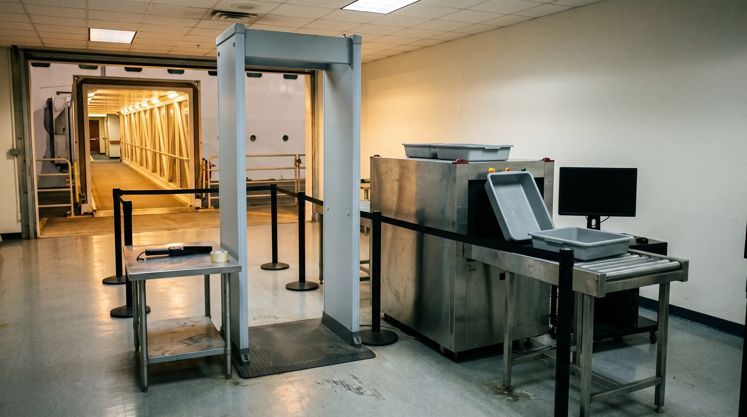 An empty security checkpoint with a walk through metal detector and a baggage scanner